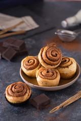 Delicious and tempting homemade cinnamon rolls with chocolate filling for christmas celebration decorated on plate and dark background