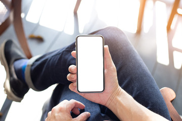 Mockup image blank white screen cell phone.man hand holding texting using mobile sitting at coffee shop.background empty space for advertise text.people contact marketing business,technology