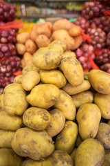 pile of fresh potato stacked at grocery market ready for sale. onion background blur selective focus