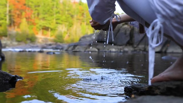 An environmentalist picking up fresh water from the river. Female concerned with protecting and preserving the natural environment