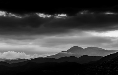 dramatic black and white landscape image of the Caribbean mountains at sunset with stormy skies in the Dominican republic.