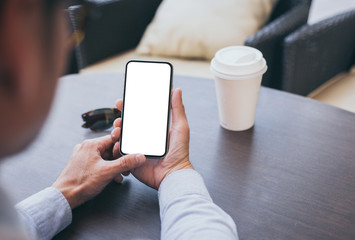 Mockup image blank white screen cell phone.man hand holding texting using mobile on desk at coffee shop.background empty space for advertise text.people contact marketing business,technology