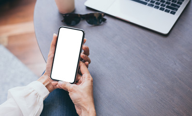 Mockup image blank white screen cell phone.woman hand holding texting using mobile on desk at coffee shop.background empty space for advertise text.people contact marketing business,technology