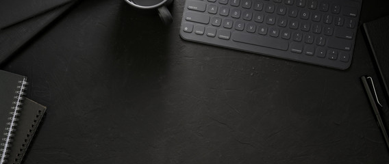 Top view of dark workspace with wireless device, office supplies and copy space
