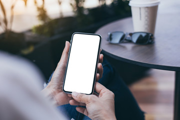 Mockup image blank white screen cell phone.woman hand holding texting using mobile on desk at coffee shop.background empty space for advertise text.people contact marketing business,technology