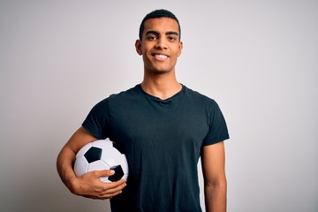 Handsome african american man playing footbal holding soccer ball over white background with a happy and cool smile on face. Lucky person. © Krakenimages.com