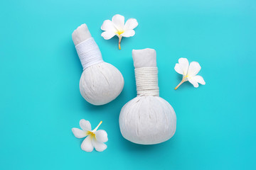 Plumeria or frangipani flower with herbal compress balls for Thai massage and spa treatment  on blue background.