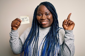 Young african american plus size woman with braids holding reminder paper with yes message...