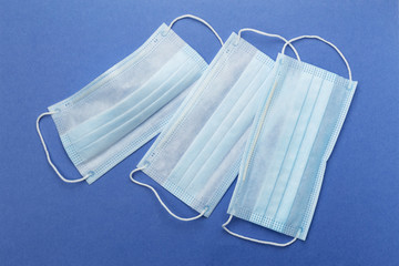 Disposable surgical mask to protect against infection. Medical protective mask, isolated on blue background. Concept for preventing virus infection.