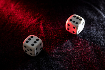 Old white dices with double six pair iluminated with red and white lights over a black background