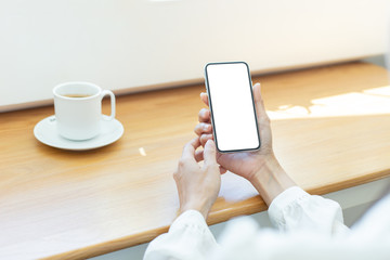 cell phone Mockup image blank white screen.woman hand holding texting using mobile on desk at coffee shop.background empty space for advertise text.people contact marketing business,technology