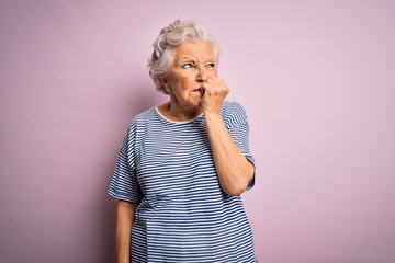 Senior beautiful grey-haired woman wearing casual t-shirt over isolated pink background looking stressed and nervous with hands on mouth biting nails. Anxiety problem.
