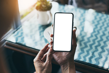 cell phone Mockup image blank white screen.woman hand holding texting using mobile on desk at coffee shop.background empty space for advertise text.people contact marketing business,technology