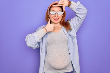 Young redhead pregnant woman expecting baby wearing funny thug life sunglasses smiling making frame with hands and fingers with happy face. Creativity and photography concept.