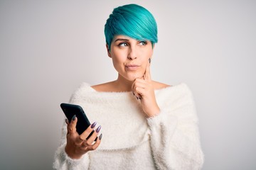 Young woman with blue fashion hair having a conversation using smartphone serious face thinking...