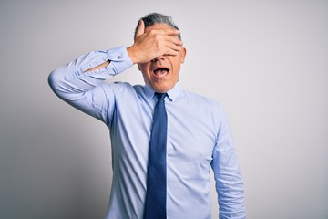 Middle age handsome grey-haired business man wearing elegant shirt and tie smiling and laughing with hand on face covering eyes for surprise. Blind concept.