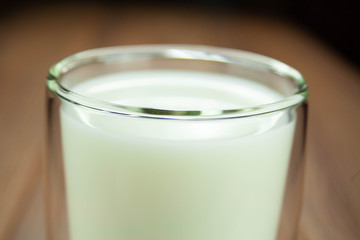 A full glass of milk with double walls top view on a wooden background