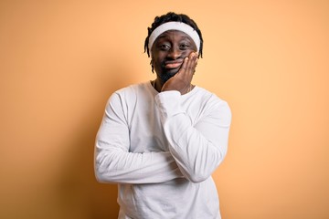 Young african american man doing sport wearing sportswer over isolated yellow background thinking looking tired and bored with depression problems with crossed arms.