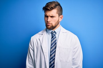 Young blond therapist man with beard and blue eyes wearing coat and tie over background skeptic and nervous, frowning upset because of problem. Negative person.