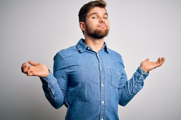 Young handsome blond man with beard and blue eyes wearing casual denim shirt clueless and confused...