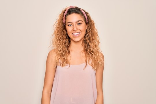 Young beautiful woman with blue eyes wearing casual t-shirt and diadem over pink background with a happy and cool smile on face. Lucky person.