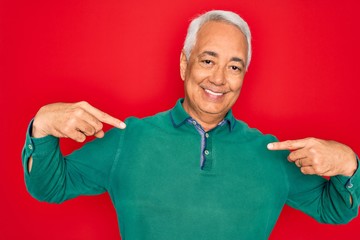Middle age senior grey-haired man wearing casual sweater over red isoalted background looking...