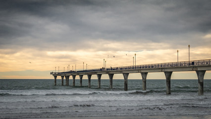 Obraz premium Massive concrete pier leading to horizon surrounded by ocean. Shot made during sunset in New Brighton Beach in Christchurch, New Zealand