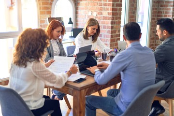 Group of business workers working together. Sitting on desk using laptop reading documents at the office