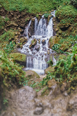 Small cascade waterfall at Tumpak Sewu with rocky foreground copyspace. Green foliage enhance scenic nature.
