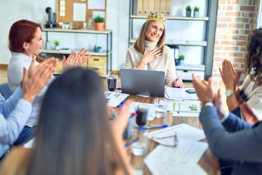 Group of business workers smiling happy and confident. Working together with smile on face applauding one of them wearing king crown at the office