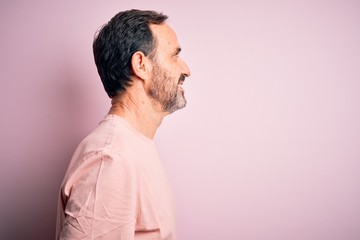 Middle age hoary man wearing casual t-shirt standing over isolated pink background looking to side,...
