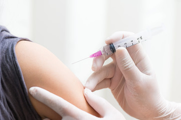 close up doctor's hand injecting for vaccination in the shoulder woman patient.Vaccine for protection HPV (Human Papillomavirus) infection.Vaccination for coronavirus treatment.