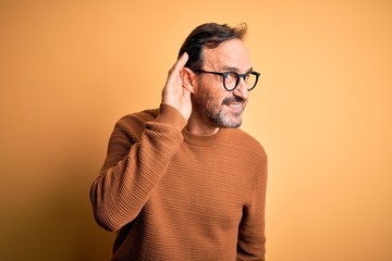 Middle age hoary man wearing brown sweater and glasses over isolated yellow background smiling with...