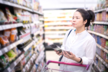 Asian beautiful woman using smart phone shopping in super market