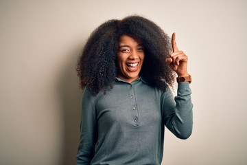 Young beautiful african american woman with afro hair standing over isolated background pointing...