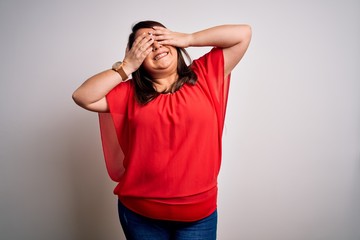 Beautiful brunette plus size woman wearing casual red t-shirt over isolated white background covering eyes with hands smiling cheerful and funny. Blind concept.