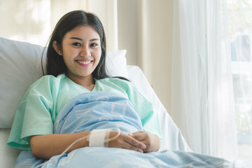 Patient happy after ill and have a health insurance. young  asian girl lying on bed in hospital and...