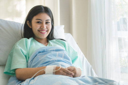 Patient happy after ill and have a health insurance. young  asian girl lying on bed in hospital and feeling relaxed after recovery from emergency sick.