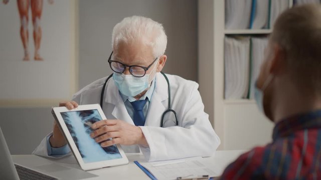 Doctor showing chest x-ray to male patient on tablet