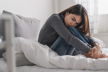 Fototapeta premium Suffer from depression , mental health problem. asian young woman sitting on the bed feeling depressed.