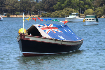 Fototapeta premium Boats in a river, one of the boats has the inside of the boat is covered by a tarp with the Australian flag