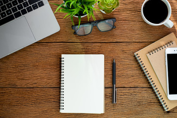 Top view from above of Blank notebook with laptop, glasses and coffee on wood table background....