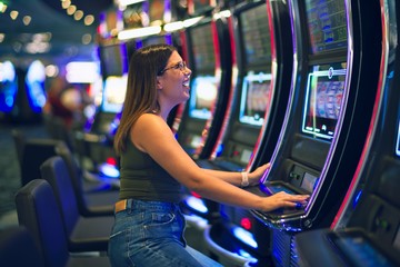 Young beautiful woman smiling happy and confident. Sitting with smile on face playing slot machine...