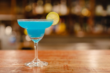 summer alcohol fresh fruit drink. blue color cocktail decorate with lime  on counter bar have a...