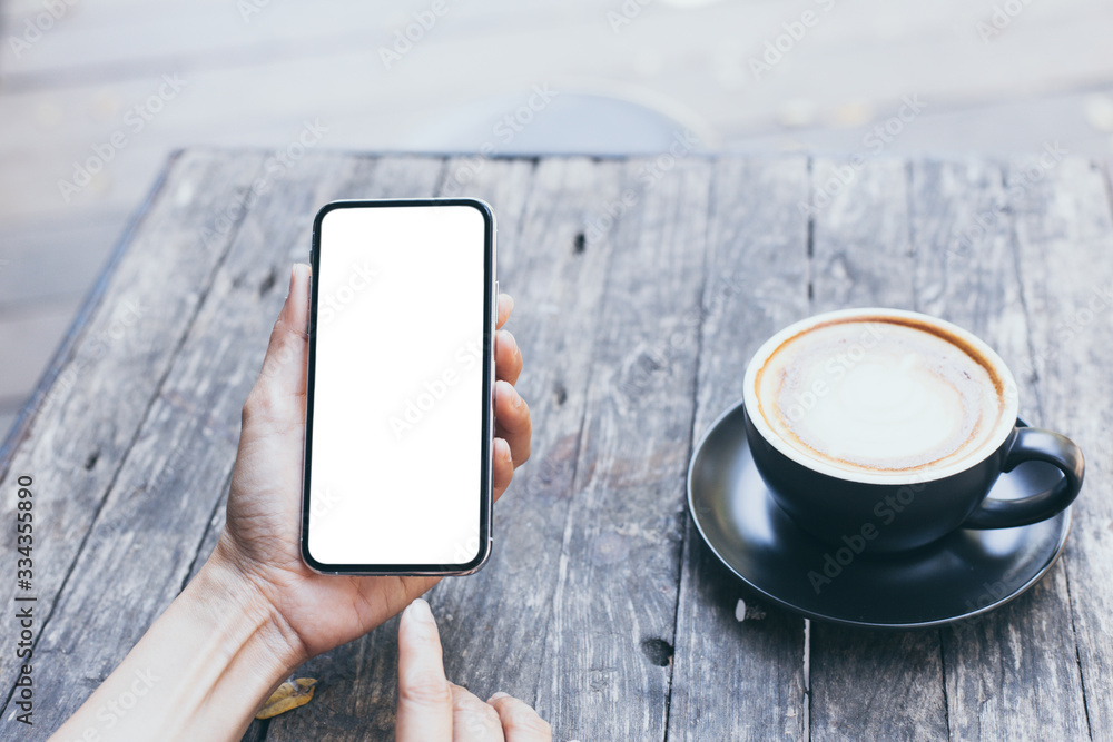 Wall mural cell phone mockup image blank white screen.woman hand holding texting using mobile on desk at coffee