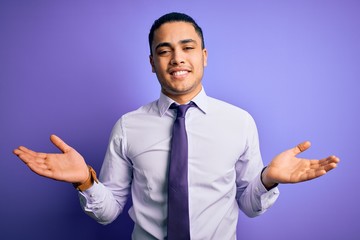 Young brazilian businessman wearing elegant tie standing over isolated purple background smiling showing both hands open palms, presenting and advertising comparison and balance