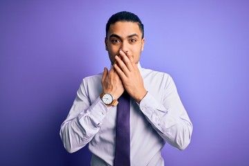 Young brazilian businessman wearing elegant tie standing over isolated purple background laughing and embarrassed giggle covering mouth with hands, gossip and scandal concept