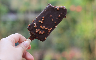 Hand hold chocolate ice cream. With blurred background.ฃ
