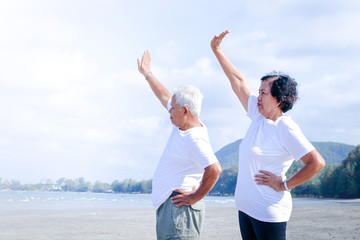 Elderly couple Morning exercise on the beach by the sea Both live a happy life. Health care concept