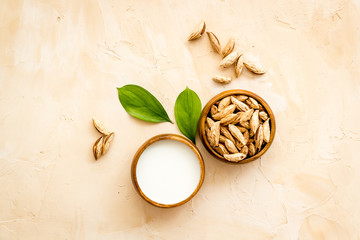Alternative milk made from almond. Drink near unpeeled on beige table top-down